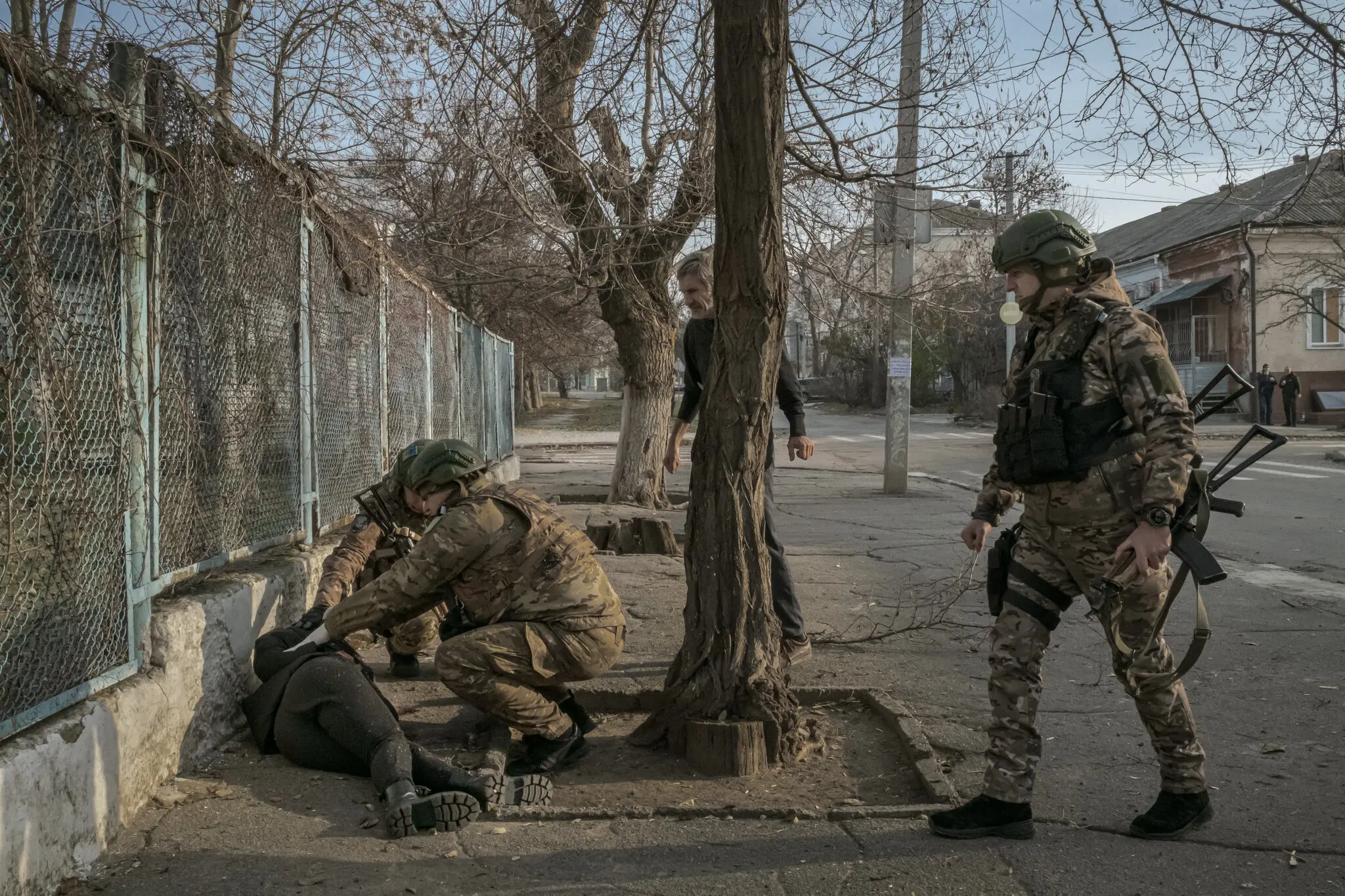 Цього місяця в Херсоні українські військові наближаються до бездиханної жінки через кілька хвилин після того, як біля школи впала ракета, а поблизу все ще чути вибухи.